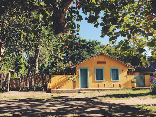 A yellow house under the trees on the Quadrado — Trancoso, Brazil