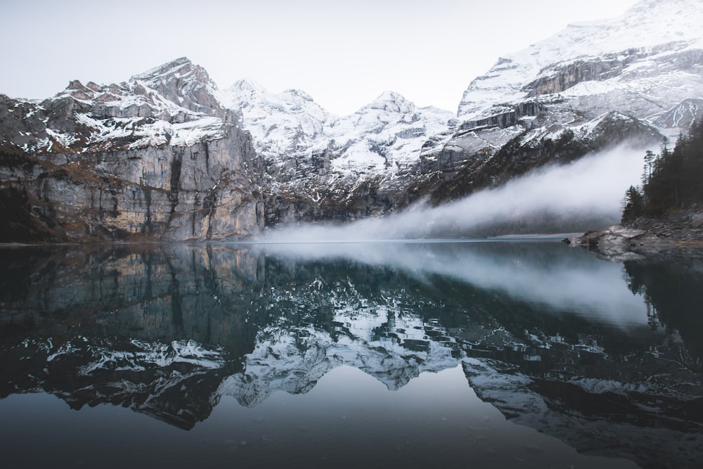 snow covered mountain near reflecting on water during daytime