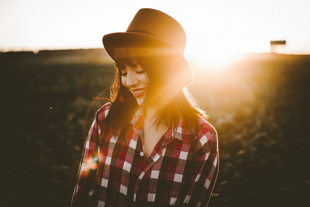 Um, jovem, morena, senhora, desgastar, xadrez, e, um, chapÃ©u, ficar, em, um, campo, com, um, pÃ´r do sol, brilhar, atrÃ¡s de, dela