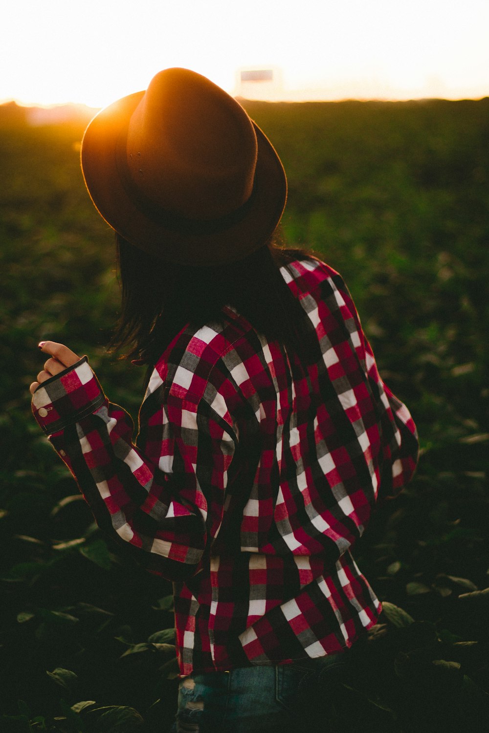 Mujer con sombrero y camisa a cuadros sobre hierba verde