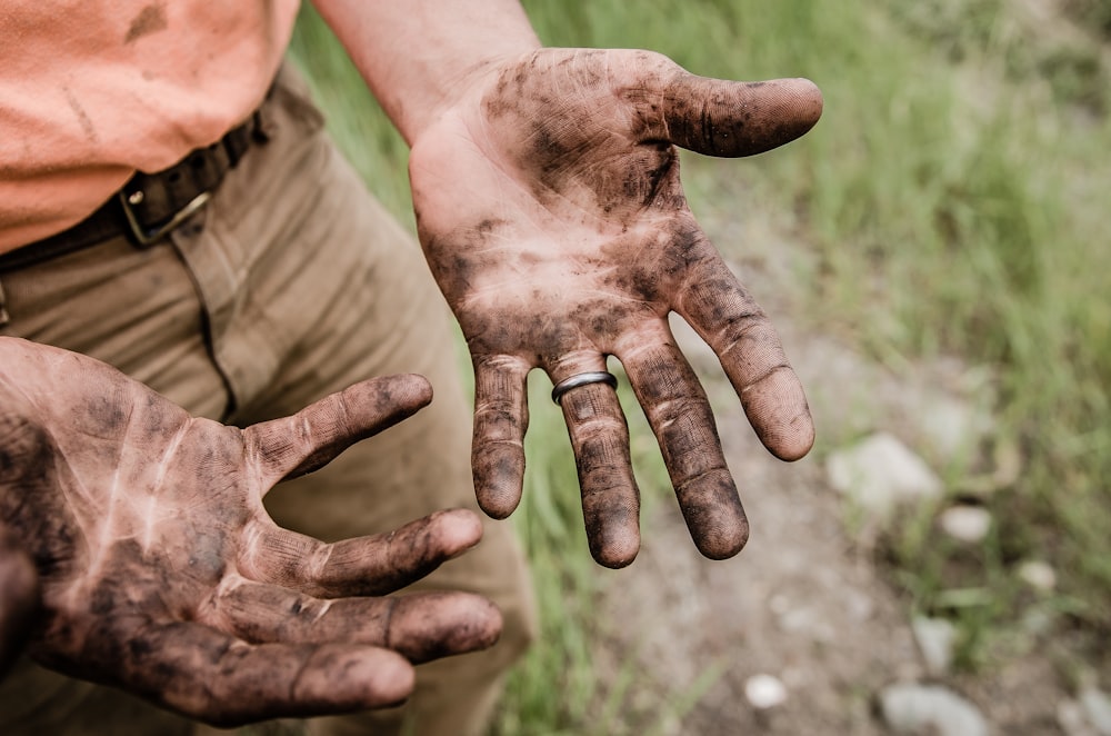 Un uomo con le mani coperte di fango