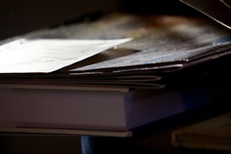 A stack of diverse academic books with a magnifying glass highlighting fine print.