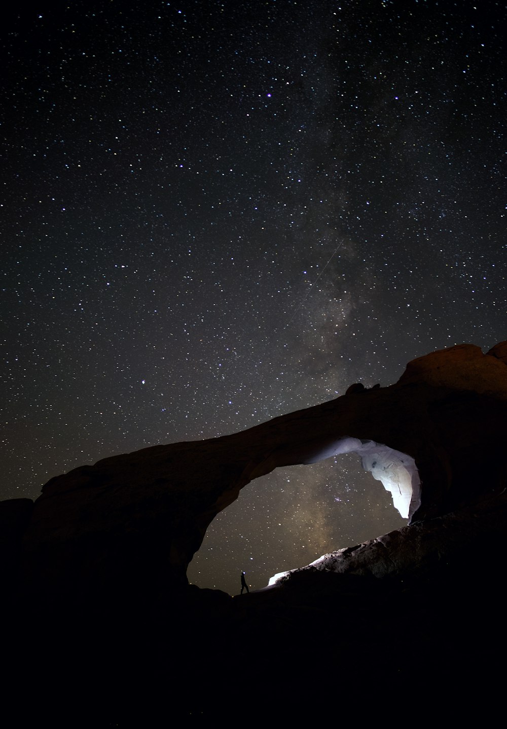 silhouette photo of person stand on rocks during nighttime