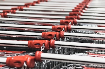 Multiple rows of empty shopping carts are aligned in a symmetrical pattern. The carts have red handles, metal frames, and appear to be organized neatly.