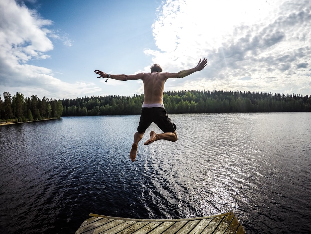 man jumping through body of water