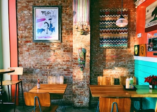 two square brown wooden dining tables near brown brick wall