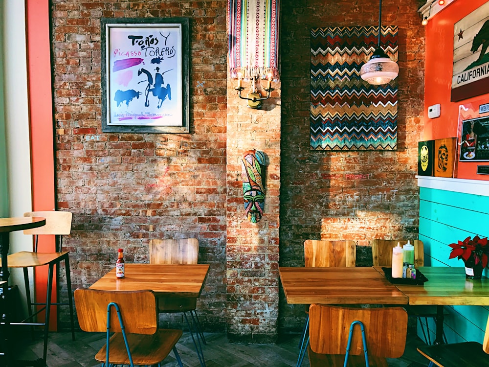 two square brown wooden dining tables near brown brick wall