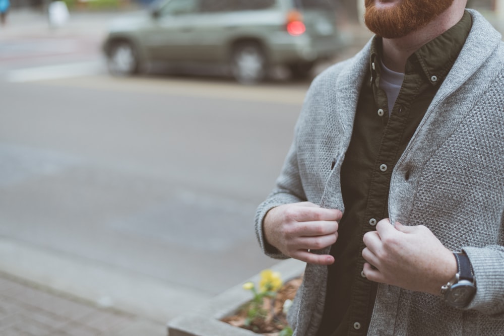 man holding his gray cardigan