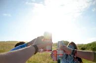 Friends laughing and clinking Brissa cans together at a casual outdoor summer gathering.