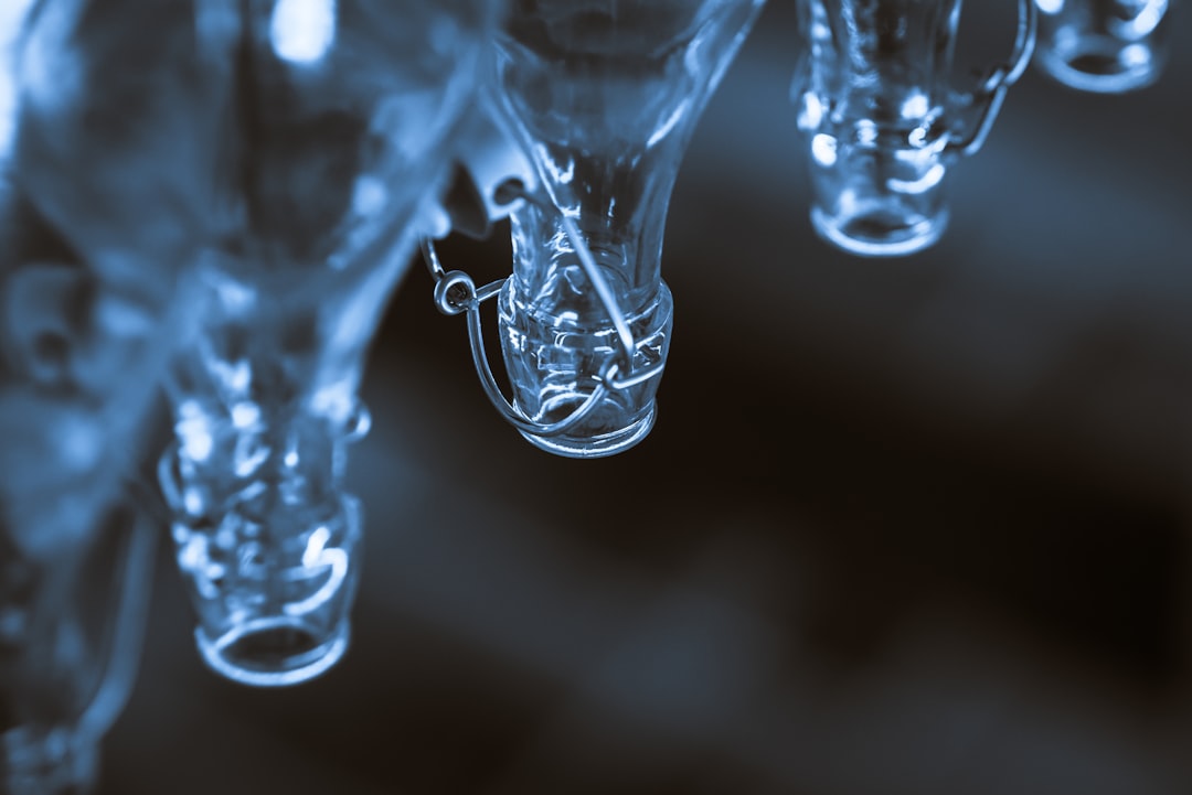 macro shot photography of clear glass bottles, Wandering through the grocery store and saw these wonderful bottles on the highest shelf. The row was much longer than depicted, but the focus on the central bottle is super attractive to me. Left room for copy space. Hope it goes go good use for some project!