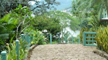 Wide shot of a garden pathway paved with smooth palimanan stones surrounded by greenery.