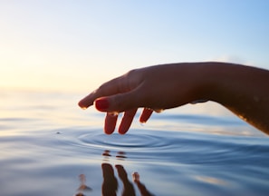 person about to touch the calm water