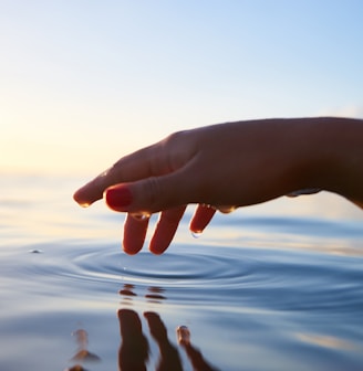 person about to touch the calm water