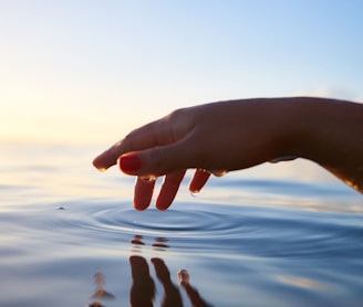 person about to touch the calm water