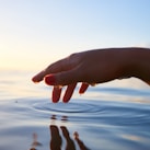 person about to touch the calm water