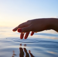 person about to touch the calm water