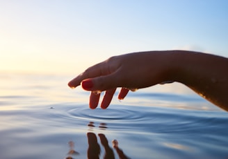 person about to touch the calm water