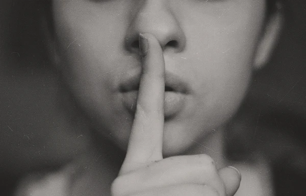 Black and white close-up of a woman with her finger to her lips