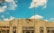 A weathered building facade with the text 'THE NEWS BROOKLYN GARAGE' displayed prominently. The building has a rustic and deteriorated look with visible grime and wear. Several large windows with rusted grilles are visible along the front, and a tall streetlight is positioned in the center of the image. The sky above is bright blue with scattered clouds.