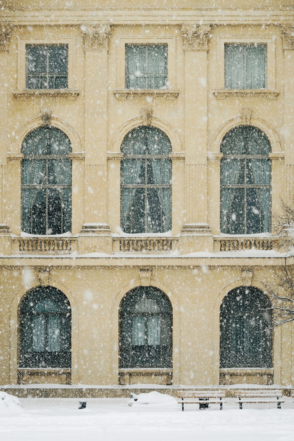 雪が積もったベージュのコンクリート製3階建ての建物の写真