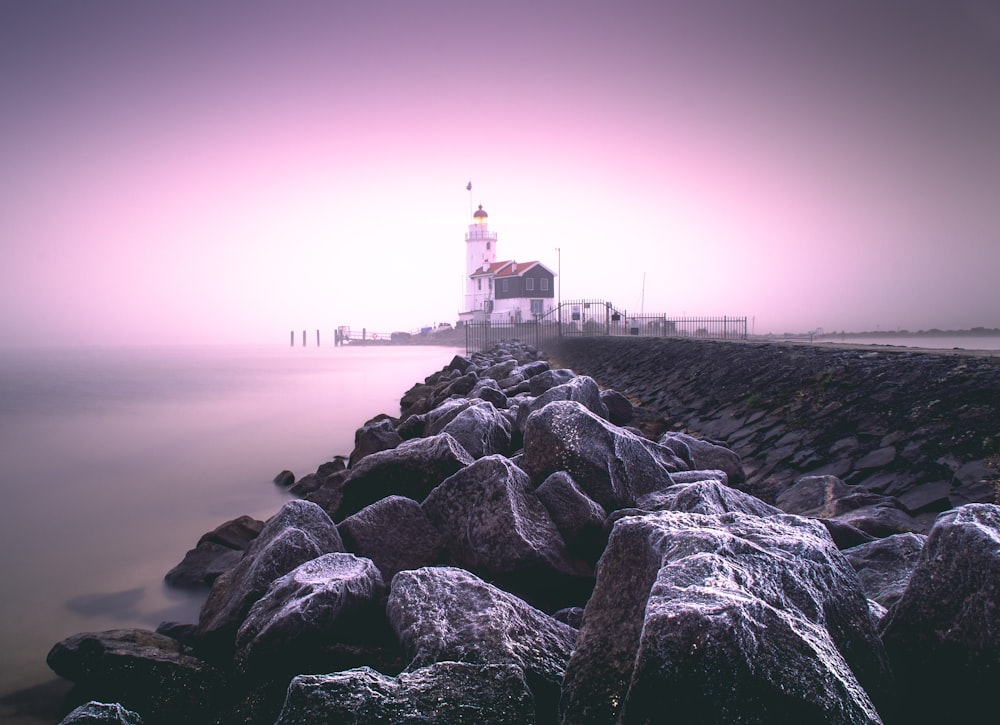 white and red lighthouse near body of water during sunset