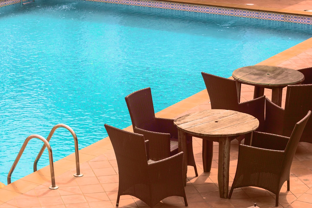 Rattan chairs around small wooden tables by a pool