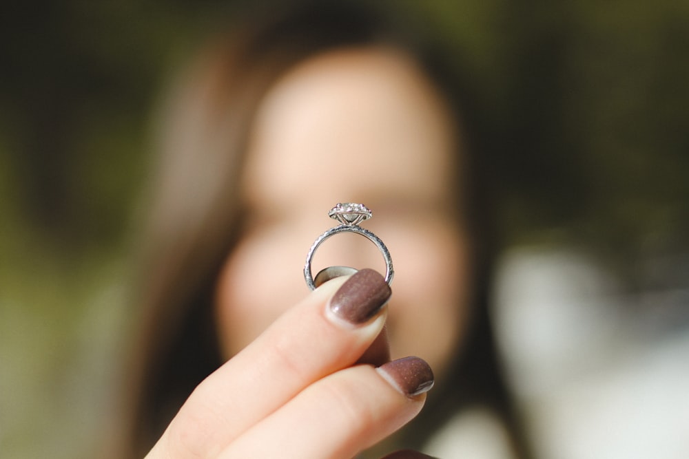 Flachfokusfotografie einer Frau, die einen Diamantring hält