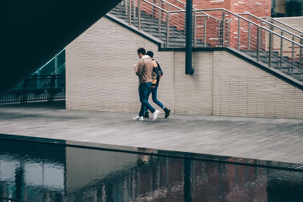 two man walking beside stair and body of water at daytime