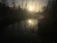 A serene sunrise over the Ganges river with mist rising among lush green hills.