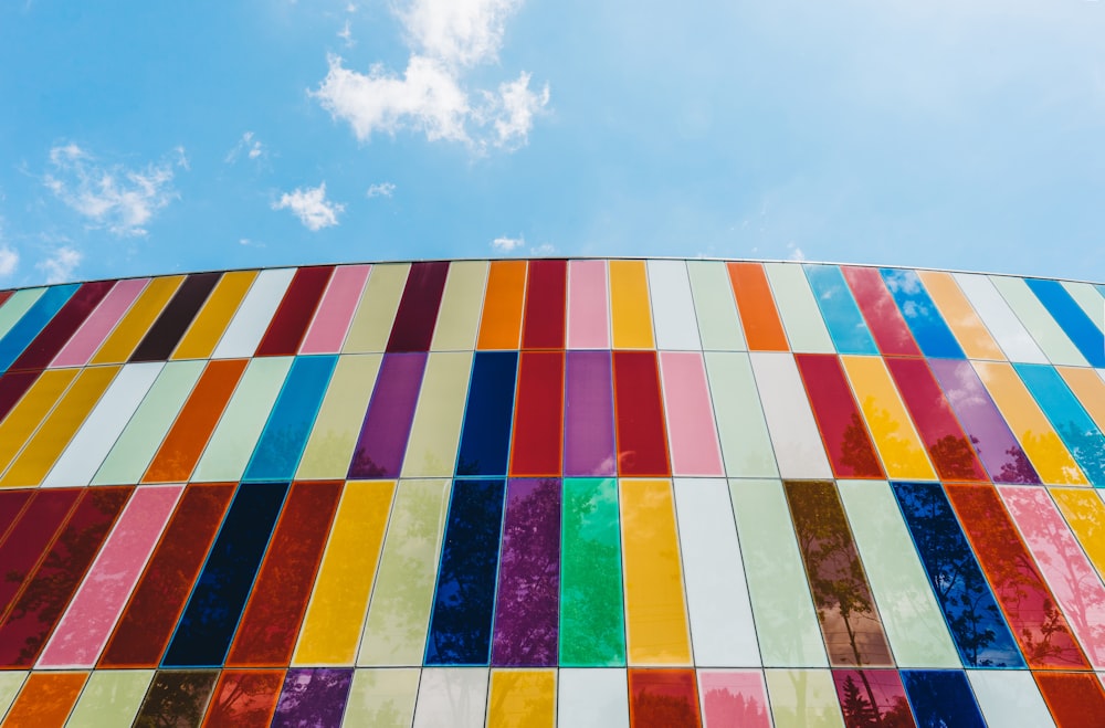 Photographie en contre-plongée d’un bâtiment avec un mur-rideau rouge, vert et blanc