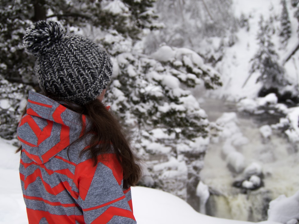 Mujer de pie en el campo de nieve cerca de los árboles