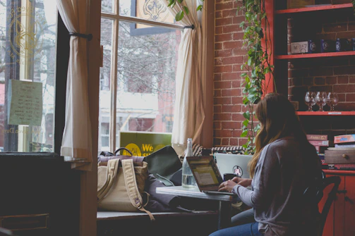 A traveler peacefully working on a laptop in a cozy nook with easy access to charging ports and soft lighting.
