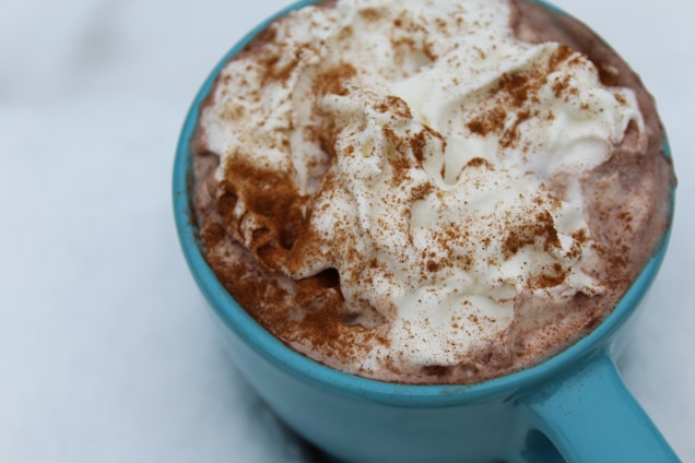 Close-up of a hot chocolate bomb melting in a steaming mug, releasing colorful sprinkles and rich cocoa.