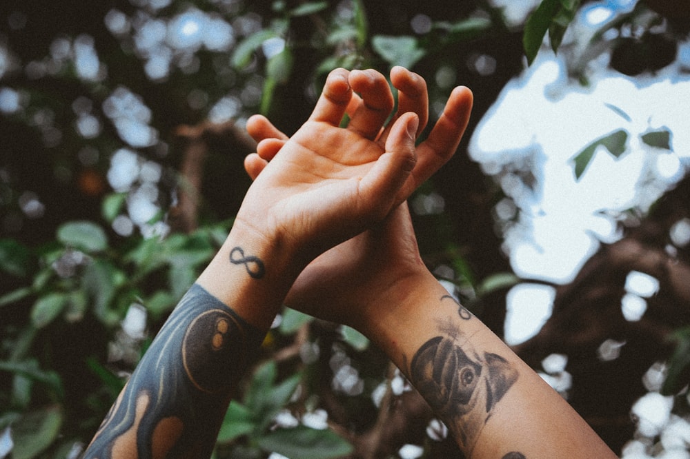 person raising his hands near tree