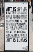A black and white poster with various motivational phrases about art arranged in different fonts and sizes. Words include 'Art is love', 'Art is life', 'Art is a journey', among others. The poster has a minimalist design and is placed outside on what appears to be a city street.