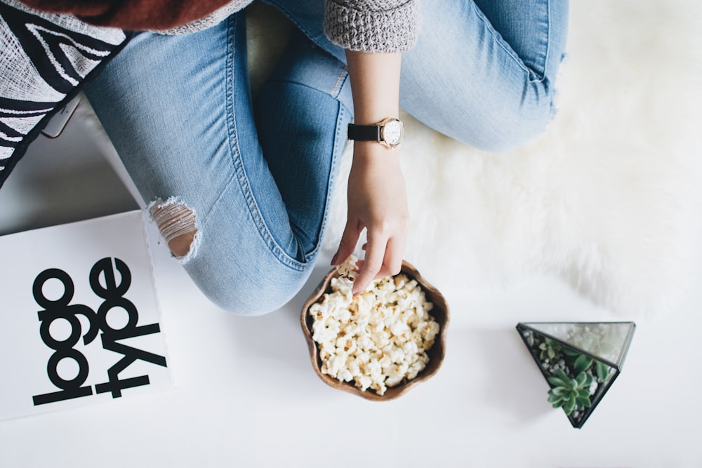 Person mit Popcorn auf Schüssel