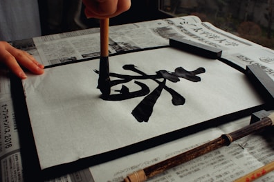 A student practicing calligraphy strokes with a traditional brush on rice paper in a serene dojo.
