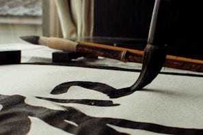 Students practicing Japanese calligraphy with brushes and ink in a bright classroom