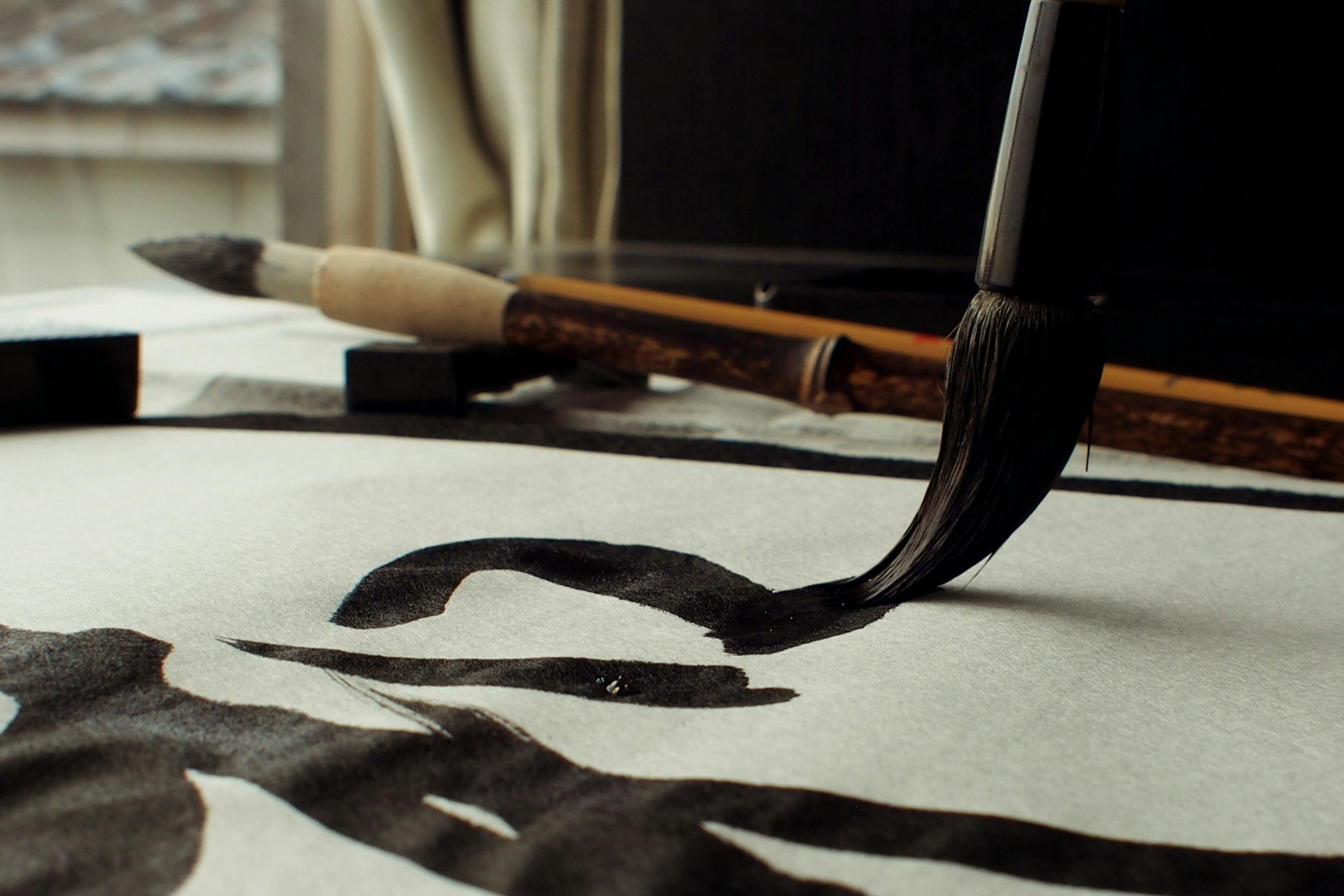 A close-up shot of a brush gracefully painting elegant Chinese characters on rice paper, with soft natural light highlighting the ink's texture.