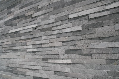 An extensive wall made of stacked, elongated stone tiles arranged in a staggered pattern. The tiles vary slightly in shade, creating a textured and layered appearance.