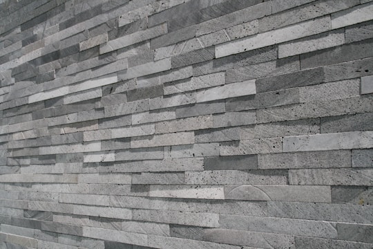 An extensive wall made of stacked, elongated stone tiles arranged in a staggered pattern. The tiles vary slightly in shade, creating a textured and layered appearance.