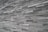 An extensive wall made of stacked, elongated stone tiles arranged in a staggered pattern. The tiles vary slightly in shade, creating a textured and layered appearance.