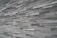 An extensive wall made of stacked, elongated stone tiles arranged in a staggered pattern. The tiles vary slightly in shade, creating a textured and layered appearance.