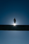 silhouette of man standing on bridge