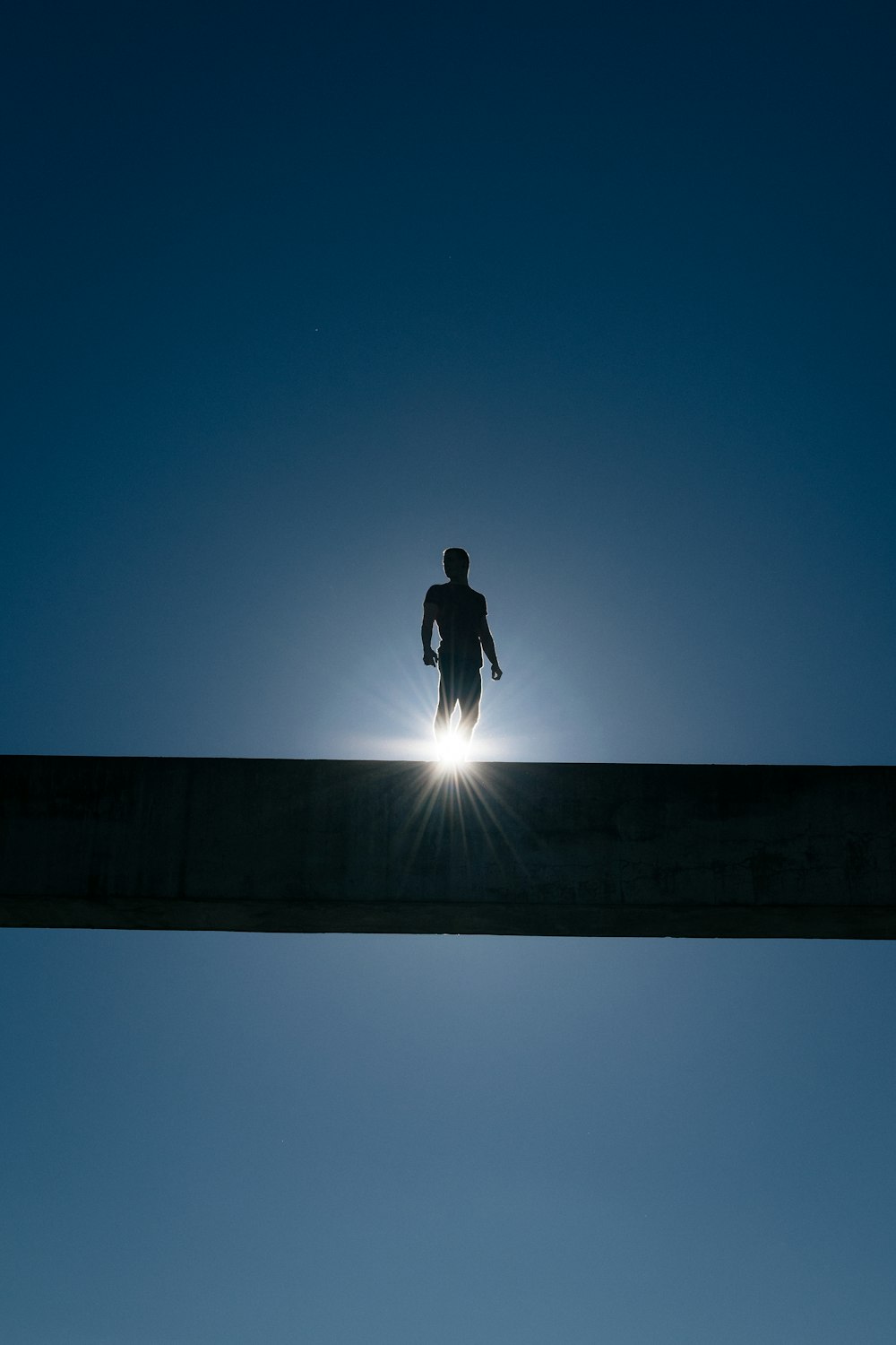 silhouette of man standing on bridge