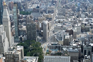 Aerial view of a bustling city with various buildings and green spaces.