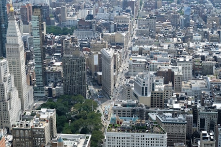 Aerial view of a bustling city with various buildings and green spaces.
