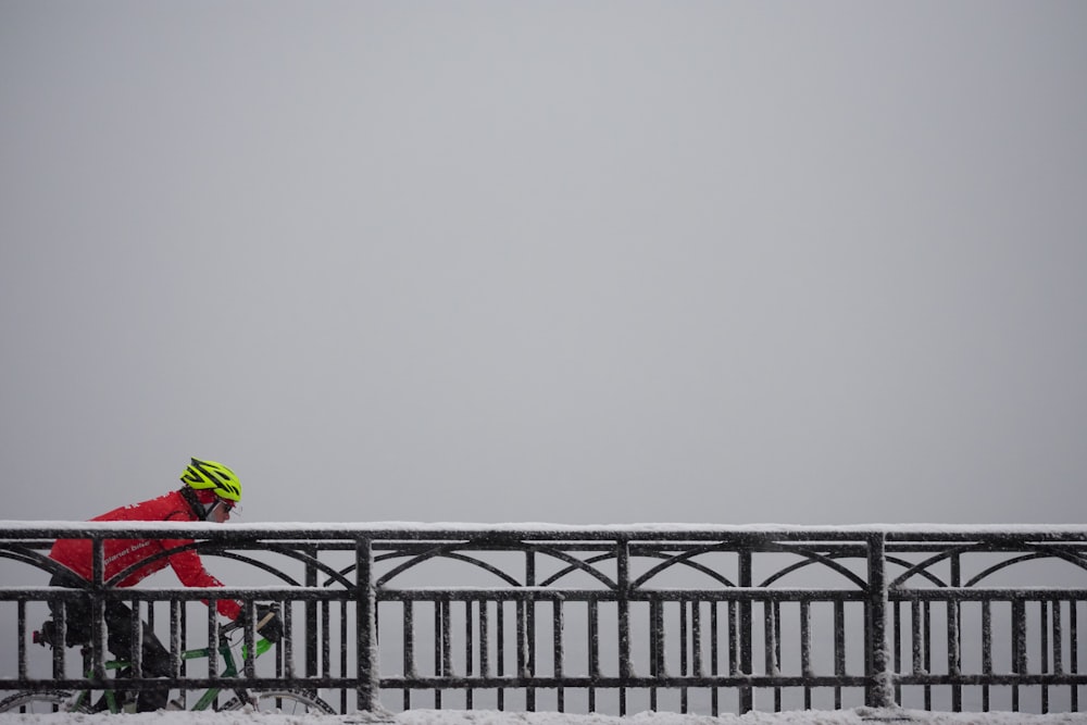 Mann in roter Jacke fährt Fahrrad auf Brücke