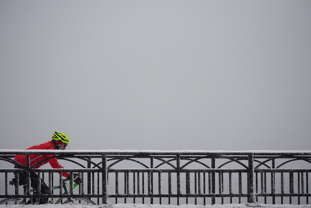 man in red jacket riding bike on bridge