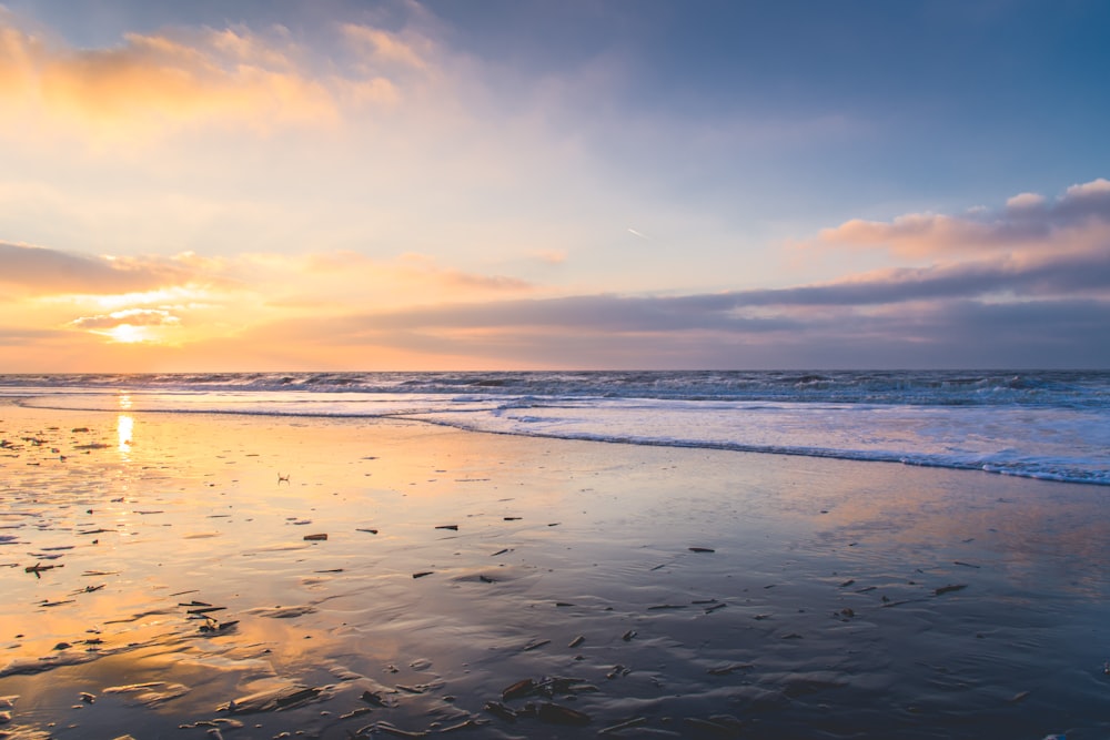 sea waves crashing on shore during sunset